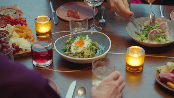 Family-style dinner with salad and pasta dishes at a candlelit table.