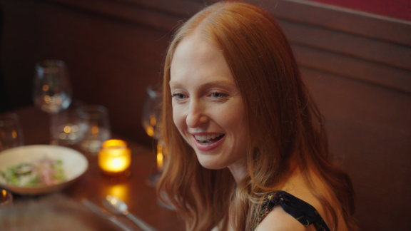 Guest smiling while dining at Metro Private Cinema, surrounded by candlelight and plates
